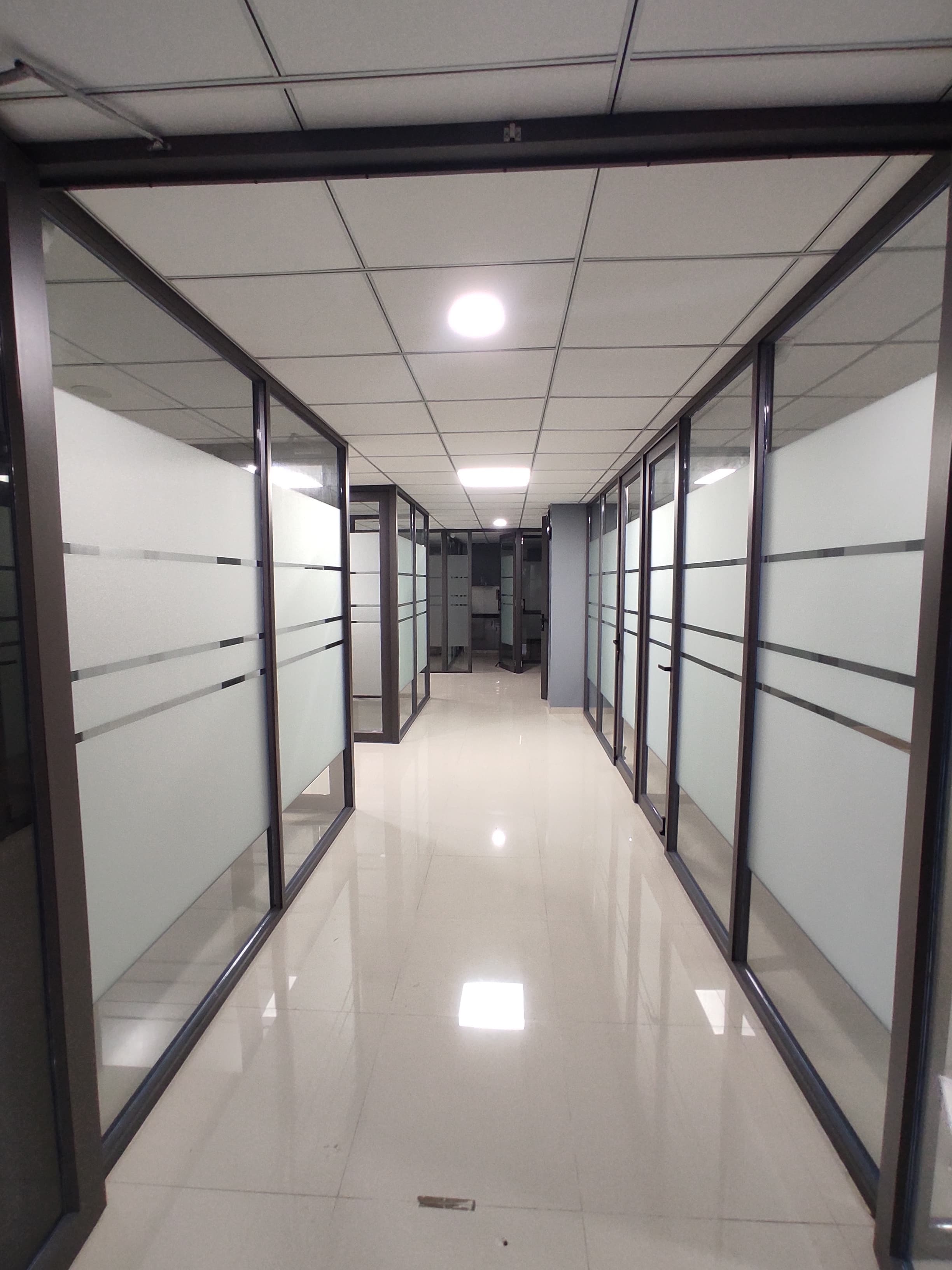 Long corridor lined with glass-partitioned cabins